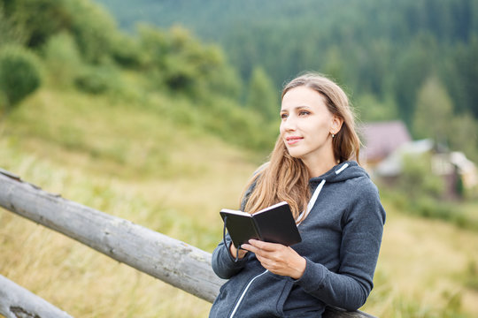 Young woman making notes standing outdoors