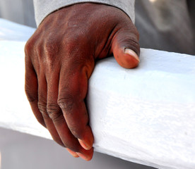 Dunkle Männerhand auf einem weißen Balken 