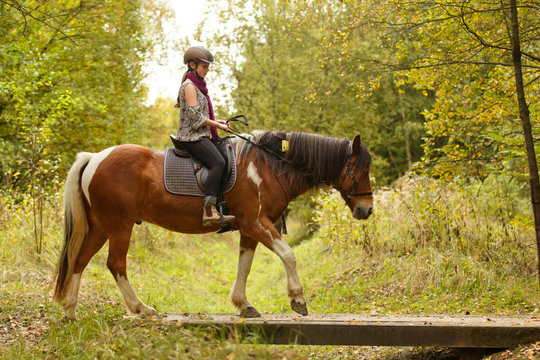 Junge Reiterin mit Schecke im Wald
