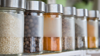 Spices, seasonings in small glass jars on wooden box