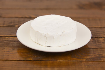 Fresh brie cheese with white mold on a white background