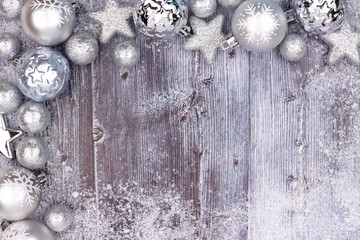 Silver Christmas ornament top corner border with snow frame on a rustic wood background