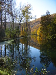 Fototapeta na wymiar Tranquil river scene with reflected trees in the Dordogne region of France in late autumn 