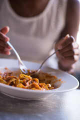 a young African American woman eating pasta