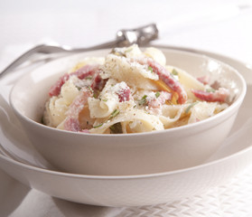 Pasta Carbonara with bacon, ham and cheese on white plate 