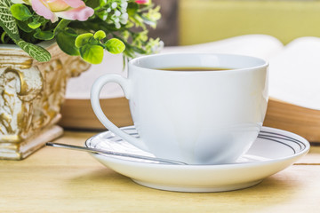 a cup of  coffee with cookies and book on wooden table