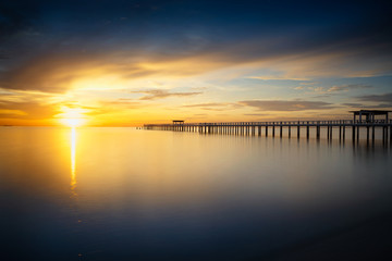 Fototapeta na wymiar Wooden bridge into the sea at sunset