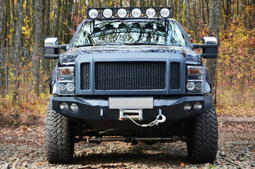 SUV amongst Fall foliage. Autumn leaves on ground. Off-road car on the background of autumn wood © mehaniq41