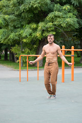 Fototapeta premium muscular sports man skipping rope outside