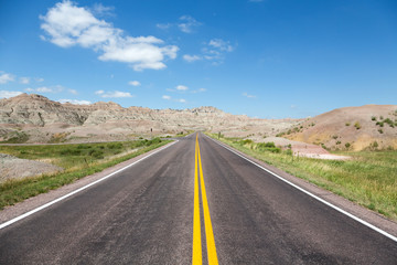 Fototapeta na wymiar A road cutting through rolling hills in the Badlands of South Dakota on a summer day. 