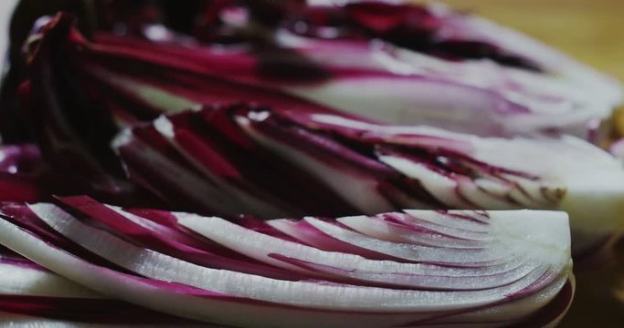 Macro close up slider of fresh juicy wet chicory slices on a wooden kitchen table