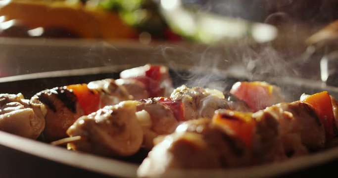Super slow motion of skewers of meat with vegetables cooked on a spit in a pan