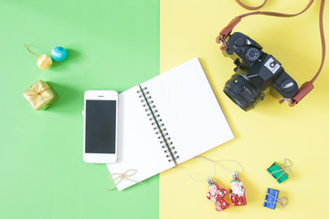 Flat lay of empty notebook with smartphone, camera and Christmas decorations