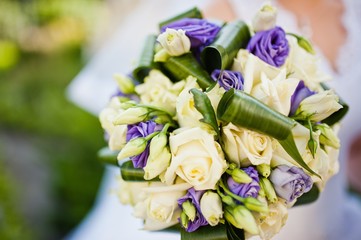 Violet wedding bouquet on hand of bride