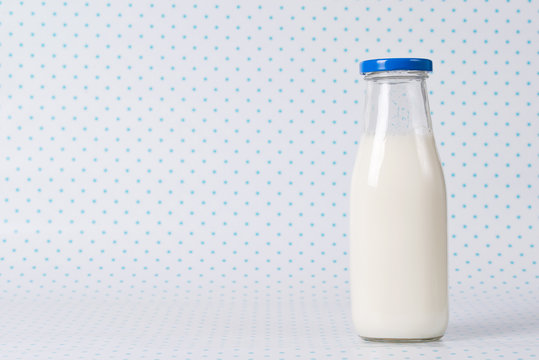 Bottle of milk with blue cap on polka dots background