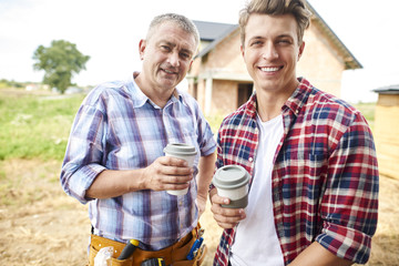 Two of carpenters are having coffee break