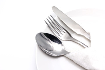 Knife, spoon and fork with serviette over dish, isolated on the white background with copy space for text.