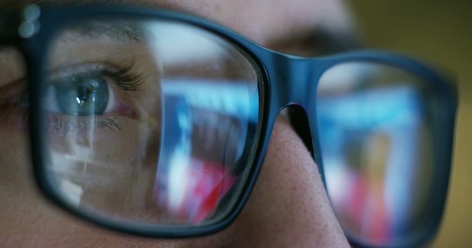 Close up of young businessman with blue eyes wearing the glasses looking on the waveform lines expressed concept of stock market, growth stock market, economic profits, stock exchange 