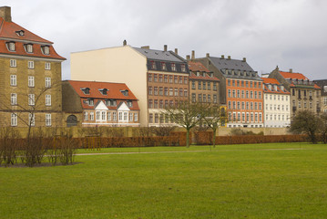 The nice park and the street with bricks houses behind the green fence in the center of Copenhagen, near the Rosenborg Castle, Denmark