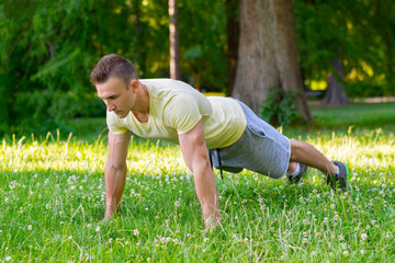 Handsome man doing push-ups at the park