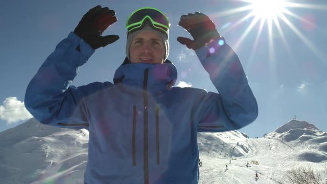 PORTRAIT: Cheerful snowboarder taking off his ski goggles, smiling into camera