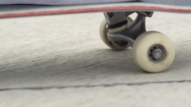 EXTREME CLOSE UP DOF: Unrecognizable skateboarder skating along the street