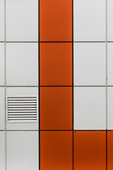 Wall of painted metal panels with ventilation outlet