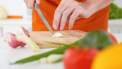 Closeup of man's hands chopping the garlic with knife.
