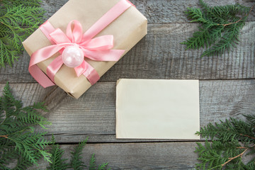 Obraz premium Preparation for Christmas holiday. Christmas gift box with pink ribbon and decor. Blank for you greetings, wishes. Top view and copyspace. Flat lay.