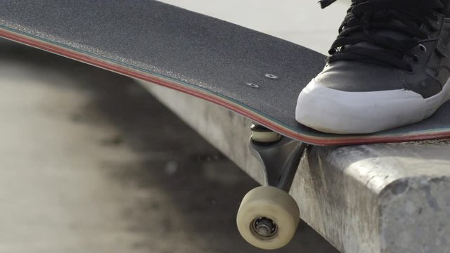 SLOW MOTION EXTREME CLOSE UP DOF: Skater grinding with skate on concrete bench