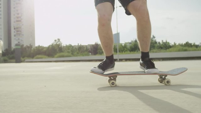 SLOW MOTION CLOSE UP: Skateboarder jumping and doing tricks on sunny city street