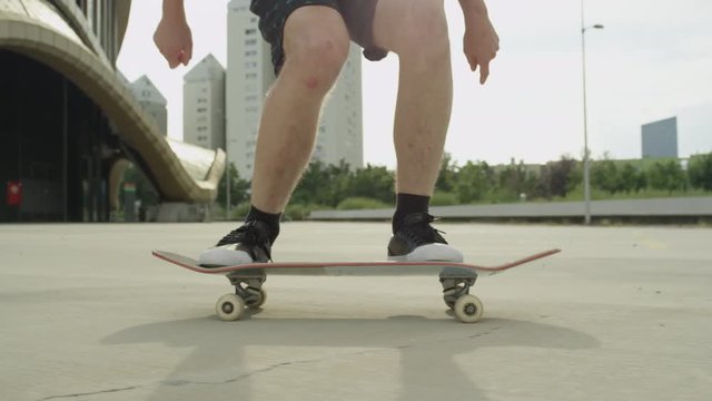 SLOW MOTION CLOSE UP: Skateboarder skating and jumping tricks on city street