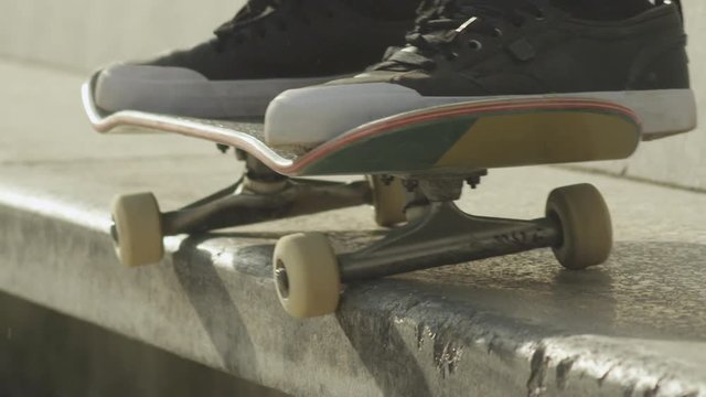 SLOW MOTION CLOSE UP: Skateboarder  jumping and riding  concrete bench in city