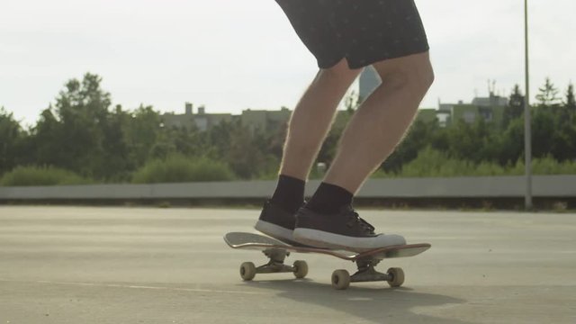 SLOW MOTION CLOSE UP DOF: Skateboarder jumping and doing a kickflip in a city
