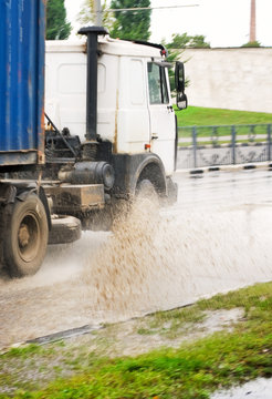 image of truck splashes through puddle on a flooded street close up