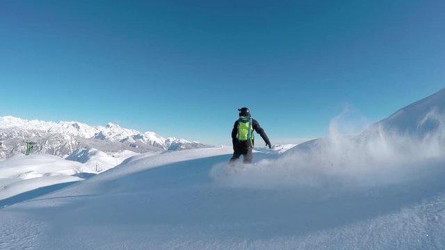 Happy snowboarder having fun riding powder snow backcountry in snowy mountains
