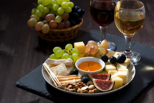 Plate with deli snacks and wine on a dark background