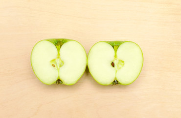 Fresh green apple cut in half close-up on a wooden background