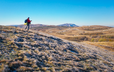 Obraz premium Photographer takes pictures on top of the mountain in autumn. 