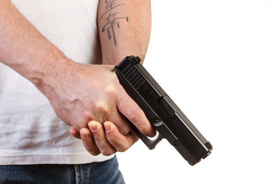 Manos de hombre sosteniendo un arma pistola en un fondo blanco. Vista de frente y de cerca. Copy space. Concepto: Problem&aacute;tica social