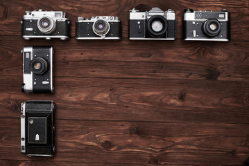Vintage cameras lying vertical in the dark wooden flat area