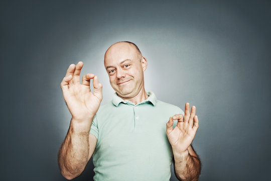 middle-aged man of average shows a sign ok hands.