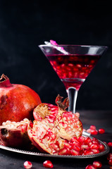 Pomegranate, cut into sections on a metal dish in the background of the shot glasses