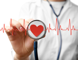 Electrocardiogram, red heart and female hand with stathoscope, closeup. Cardiology concept.