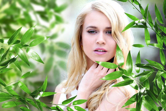 Beautiful young woman and green foliage on blurred background