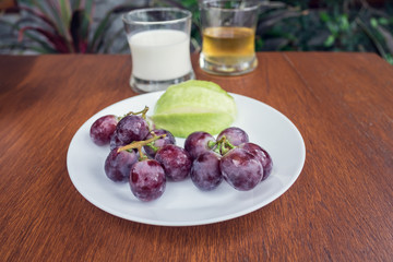Grapes with water drops in a dish with beverage background.