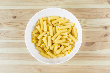 Tortiglioni pasta uncooked in bowl top view