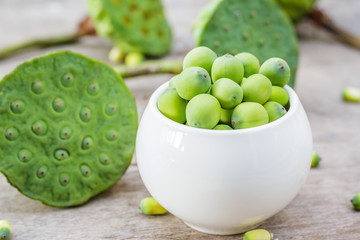 Fresh lotus seeds in vase and on wooden table background.