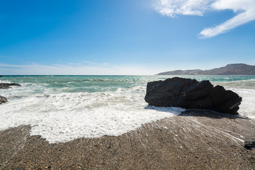 Fototapeta na wymiar A day view of a spanish mediterranean beach with a rock in a side
