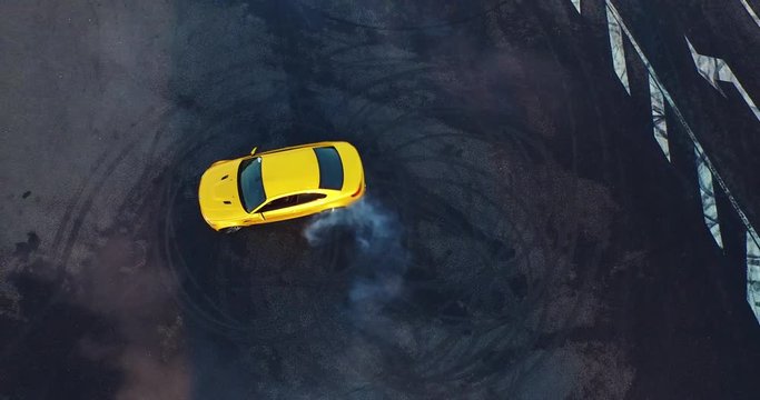 Top view of the golden car drifting on the road. Car makes a few laps. Shooting with a drone in 4k.
